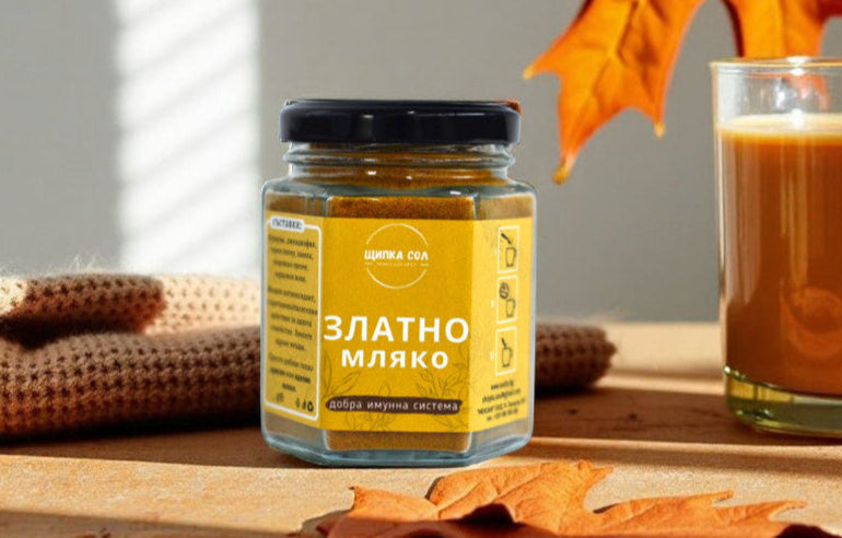 натурален микс за златно мляко от Щипка Сол поставен на маса със есенни листа наоколо. Отстрани има чаша гореща и здравословна напитка.